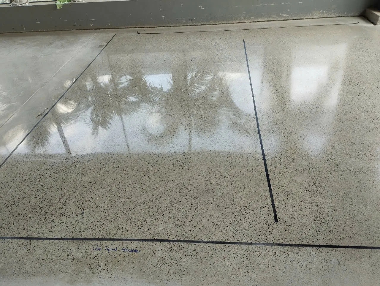 Ô mẫu sàn bê tông thi công liquid hardener, được phân vùng bằng băng keo để so sánh